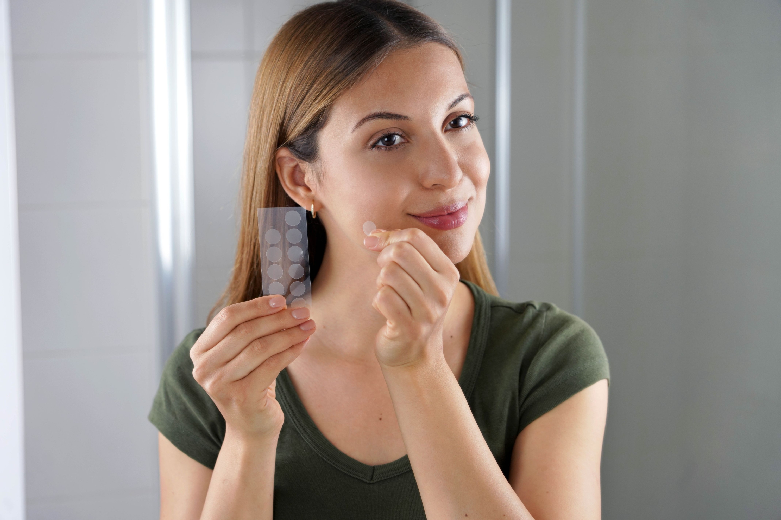 woman-holding-a-set-of-pimple-patches-while-smiling